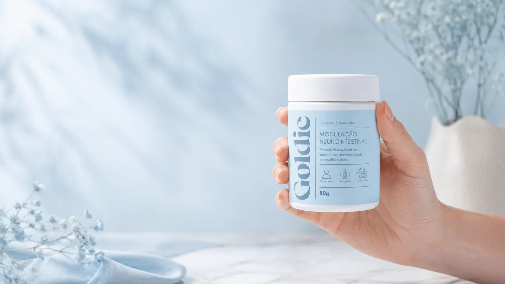 Mão segurando o pote Goldie Modulação Neurointestinal